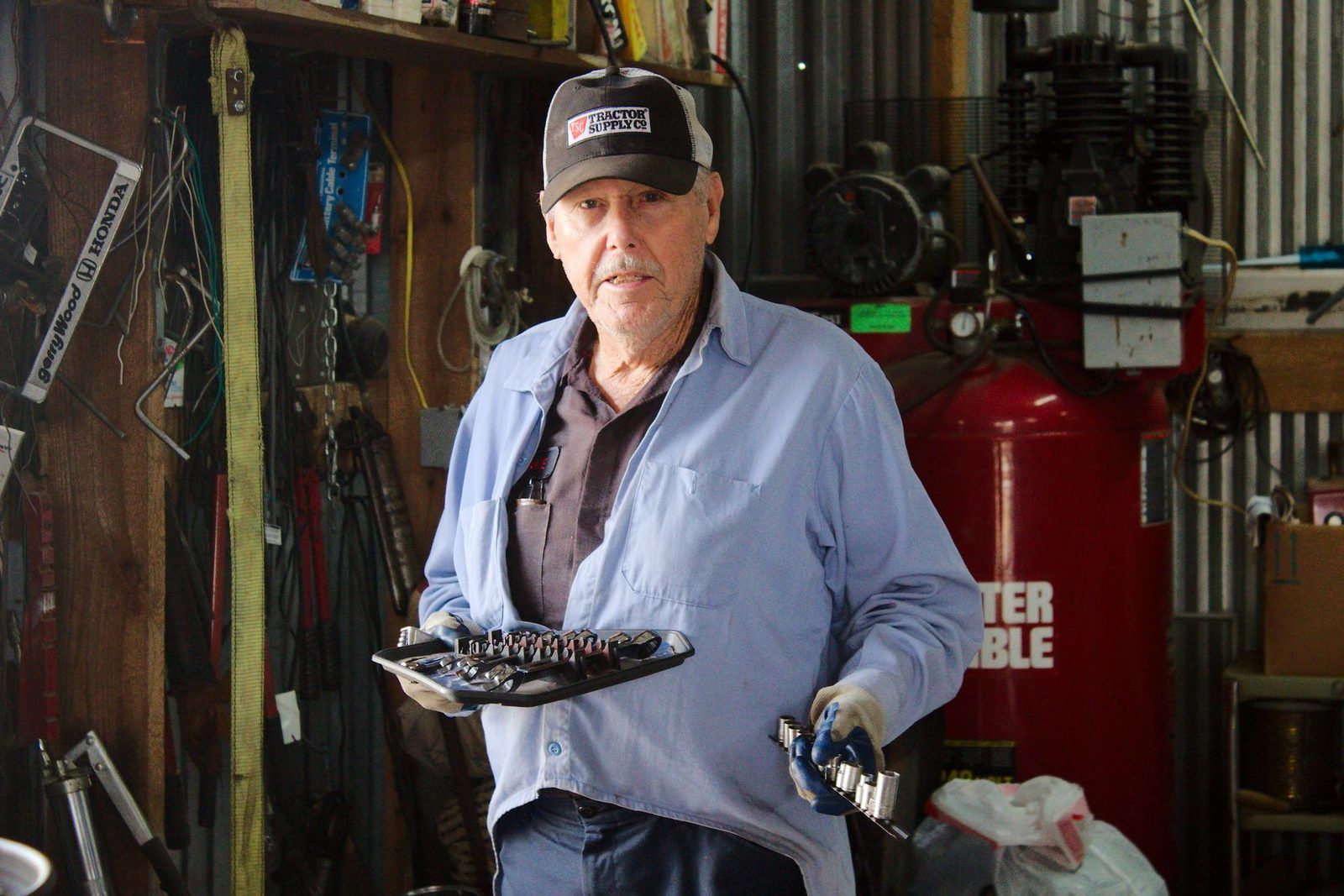 An experienced mechanic holding tools in a busy workshop