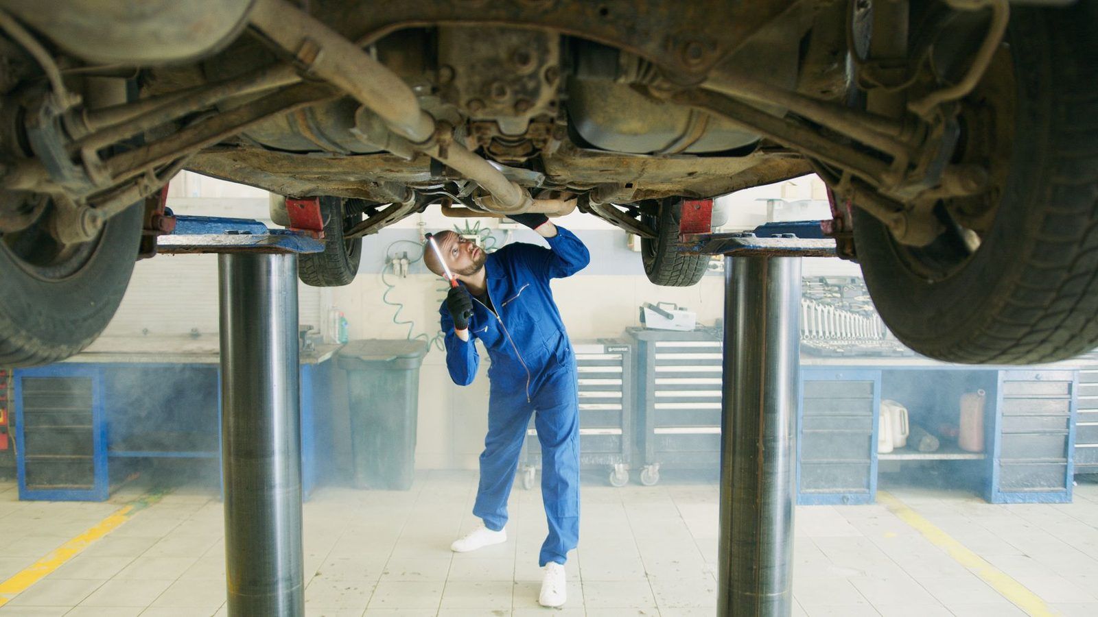 A mechanic working under a car on a lift