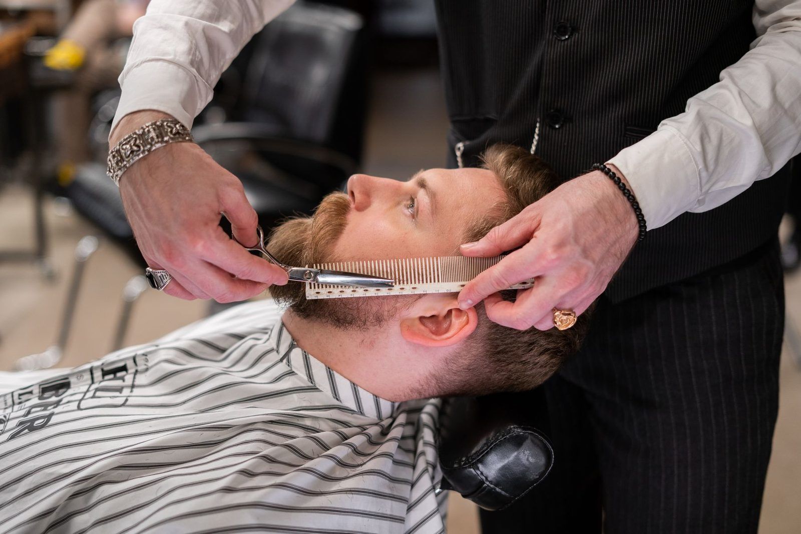 A barber trimming a client’s beard
